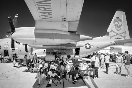 Téléchargez les photos : Les fans du spectacle aérien sont soulagés par le soleil sous l'aile d'un C-130 Hercules sur le tarmac lors de l'America's Airshow 2023 à Miramar, Californie. - en image libre de droit