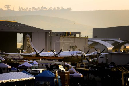Téléchargez les photos : Le soleil se lève sur un B-29 nommé Doc et les travailleurs se préparent pour l'ouverture du salon aérien de l'Amérique à Miramar, Californie. - en image libre de droit