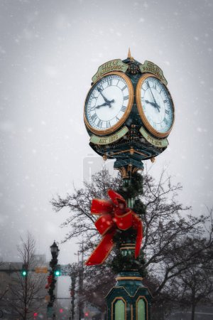 Photo for Christmas decorations on a clock during a snowstorm in the downtown area of Manitowoc, Wisconsin. - Royalty Free Image
