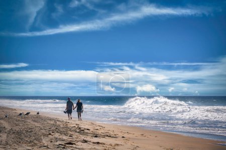 Un homme et une femme non identifiés marchent main dans la main sur le sable d'Imperial Beach, en Californie.