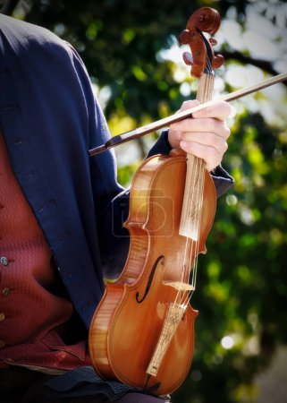 Photo for A violinist holds his instrument between song in Colonial Williamsburg, Virginia. - Royalty Free Image