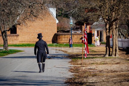 Photo for A man in a top hat walks down the street, in period clothing, at Colonial Williamsburg, Virginia. - Royalty Free Image