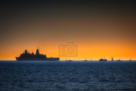 Foto de Un barco de la Marina de los Estados Unidos pasa veleros en el horizonte y justo frente a la costa de Coronado, California. - Imagen libre de derechos
