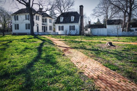 Photo for A stone walkway to colonial houses on a sunny day at Williamsburg, Virginia. - Royalty Free Image
