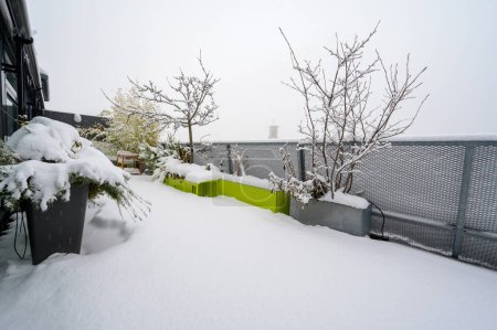 Photo for Snow-covered all-season metal furniture with snow-covered table and chairs on a roof terrace - Royalty Free Image