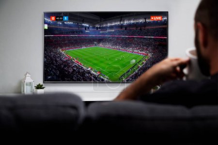 Photo for Man watching football match on smart TV. Live soccer transmission. ROSARIO, ARGENTINA - DECEMBER 18, 2022. - Royalty Free Image