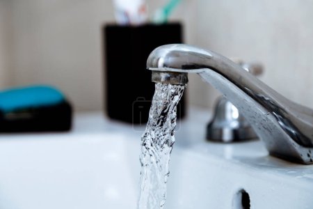 Wasserhahn im Badezimmer. Wasserhahn auf bei fließendem Wasser. Verschwendung von Trinkwasser.