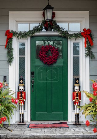 Christmas gree front door of a house home decorated for Christmas with a wreath and garland and two nutcrackers.