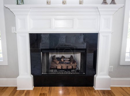 A white detailed ornate wood mantle with a gas fireplace in a new construction house,