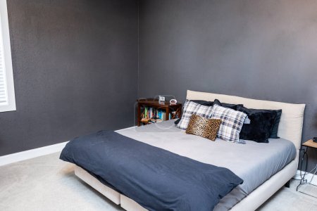A large teenage boys bedroom with navy blue walls and a queen king bed.