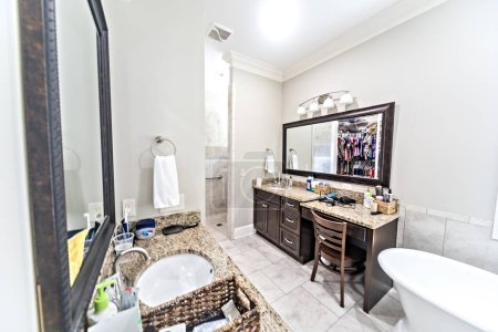 Téléchargez les photos : A large master bathroom with tile floors, dark wood vanity cabinets and a freestanding bathtub. - en image libre de droit