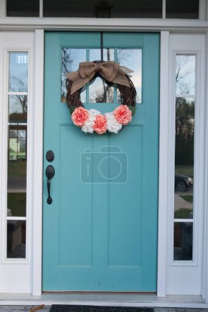 Ein Frühlingsblumenkranz auf einer hellblauen Aqua-Haustür eines Hauses.