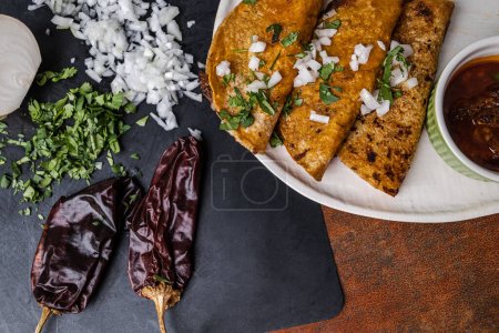 Téléchargez les photos : Une assiette de tacos de birria de bœuf mexicain de bœuf râpé, oignons, poivrons de guajillo, coriandre et bouillon avec jus de sauce à tremper. - en image libre de droit
