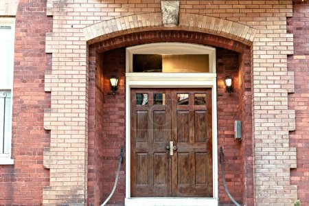 Foto de Una puerta doble de madera oscura manchada en un edificio de ladrillo rojo. - Imagen libre de derechos