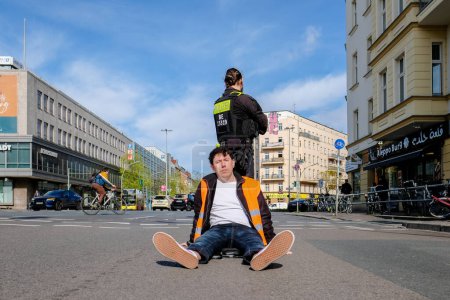 Téléchargez les photos : Berlin, Allemagne - 24 avril 2023 : Manifestants du groupe Last Generation assis dans la rue et bloquant la circulation à Berlin, Hermannplatz. Photo de haute qualité - en image libre de droit