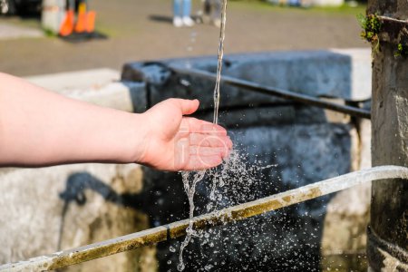 Girls hands and flowing water at the water fountain in town. High quality photo