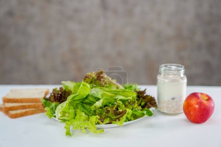 Téléchargez les photos : Salade de légumes, yaourt aux céréales, races de blé entier et pomme rouge sur fond blanc - en image libre de droit