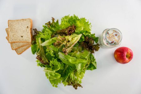Téléchargez les photos : Salade de légumes, yaourt aux céréales, races de blé entier et pomme rouge sur fond blanc, vue de dessus - en image libre de droit