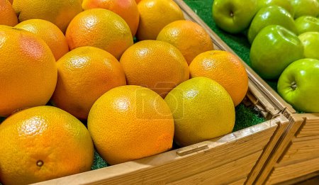 Photo for Pile of ripe oranges and apples in boxes, closeup view - Royalty Free Image