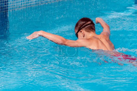 Téléchargez les photos : Boy child swimmer swim in swimming pool with butterfly style. Water sports, training, competition, activity, learn to swim school classes for children - en image libre de droit