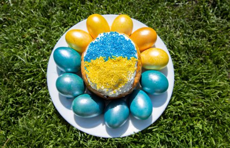 Easter cake in the colors of the Ukrainian flag and painted in yellow and blue eggs laid out around. easter concept, ukrainian traditions. Stand with Ukraine. stop the war