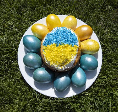 Composition with multi-colored blue and yellow Easter eggs around the Easter cake in the colors of the Ukrainian flag. Ukrainian traditions. Support Ukraine. stop the war
