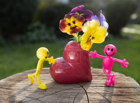 Foto de Figuras de juguete brillantes miniatura de hombres cerca de un jarrón en forma de corazón con pantaletas. pareja en el amor y el concepto de romance, amor y sentimientos tiernos. relación feliz - Imagen libre de derechos