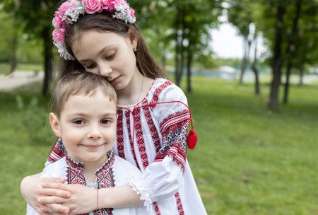 Niño de 4 años, niña de 7 años en ropa nacional bordada ucraniana se sienta abrazando. Día de la Independencia de Ucrania. Los niños deben vivir en paz y tranquilidad. Apoyo, ayuda a Ucrania. Cuidado, familia