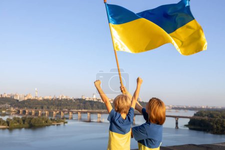 Mutter und Sohn stehen hoch oben auf dem Hausdach gegen Himmel und Dnjepr in Kiew. Patriotismus, der auf den Krieg in der Ukraine aufmerksam macht. Unterstützt die Ukraine. Independence Day. Glaube an den Sieg. den Krieg beenden