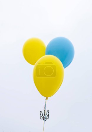 Foto de El símbolo estatal de Ucrania - un tridente atado a globos amarillo-azules vuela hacia el cielo. Apoya a Ucrania. Detengan la guerra. fe en la victoria ucraniana, la libertad y la independencia - Imagen libre de derechos