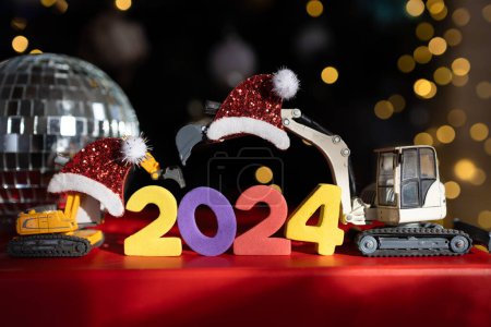 Weihnachtsferien, Festtagsstimmung. Bunte Zahlen 2024, Spielzeugbagger-Modelle, Spiegel-Discokugel, Bokeh. Glückliches neues Jahr Business-Gruß-Konzept für Baufirmen