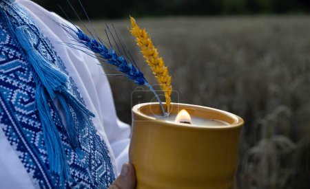 Téléchargez les photos : Bougie allumée, une chemise ukrainienne brodée et deux épis de maïs, peints dans des couleurs jaune-bleu du drapeau ukrainien. Épillets et le feu à la mémoire de la tragédie de l'Holodomor, arrêter la guerre en Ukraine - en image libre de droit