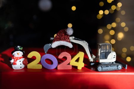 Bunte Zahlen 2024, Spielzeug-Minibagger, Souvenir-Schneemann, Bokeh. Weihnachtsferien, Festtagsstimmung. Glückliches neues Jahr Business-Gruß-Konzept für Baufirmen