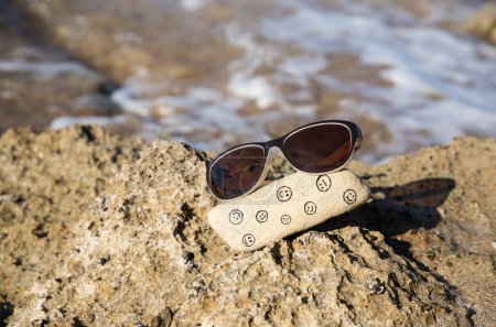 Photo for Natural stone with funny and sad faces painted on it and sunglasses on the sea coast. Hello summer, sun, vacation, positive emotions, travel. Choose your mood, be positive, digital detox - Royalty Free Image