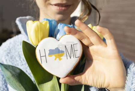 gingerbread in the shape of a heart with a map of Ukraine and the inscription Home in female hand. Peace to Ukraine. peaceful concept. Independence Day, Unity Day. Patriotism. love to motherland