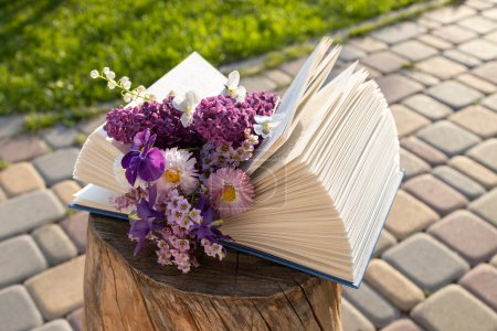 open book , between pages there is small bouquet of various flowers. concept of reading, aesthetics, wisdom and knowledge. digital detox. book day. greeting card, mother's day, romantic surprise