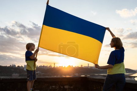 Junge und Frau stehen auf dem Dach eines Hauses in Kiew und recken die blau-gelbe ukrainische Flagge. Familie, Heimat, Einheit, Unterstützung. Die Ukrainer sind gegen den Krieg. Unterstützung der Ukraine