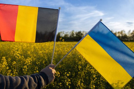 flags of Ukraine and Germany against of blooming rapeseed field and blue sky. Concept of cooperation and partnership between two European countries. Support for Ukraine in the war against Russia