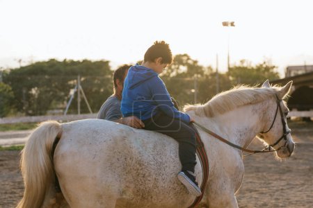 Foto de Niño con discapacidades montado en un caballo durante una sesión de terapia equina. Personas con discapacidad. - Imagen libre de derechos