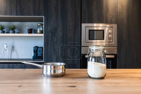 Stilvolle Kücheneinrichtung mit dunklen Holzschränken, Edelstahlgeräten und elegantem Kochgeschirr