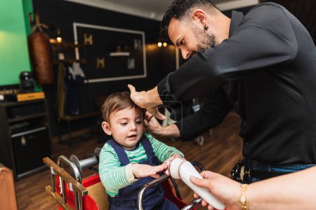 Coiffeur professionnel donne à un jeune enfant une coupe de cheveux dans un cadre de salon de coiffure, capturant un moment clé
