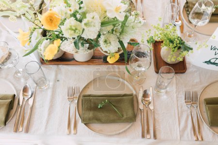 Photo for Top view on wedding table setting. Trendy event design with natural materials and garden flowers. Spring celebration decorations. Rustic linen napkins on ceramic plates with white and yellow blooms. - Royalty Free Image