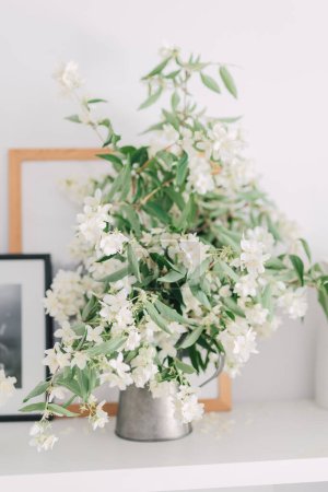 Photo for Bouquet of fresh white jasmine flowers in vase as home decoration. Indoor arrangement of branches from flowering shrub in springtime. Garden flowers decor. - Royalty Free Image