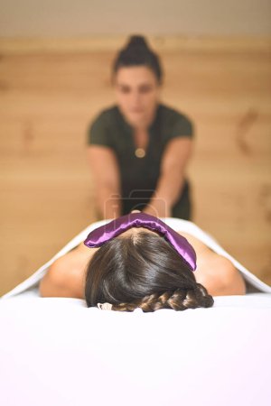 Foto de Mujer acostada con máscara de semillas sobre sus ojos recibiendo masaje tuina - Imagen libre de derechos