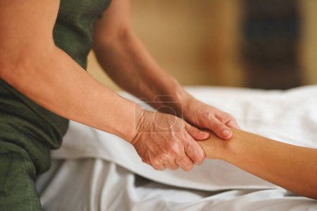 Photo for Hands of masseur pressing hands of patient in close up shot with warm tones - Royalty Free Image