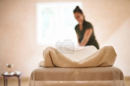 Photo for Out-of-focus background of masseuse massaging body wrapped in towel inside salon with window - Royalty Free Image