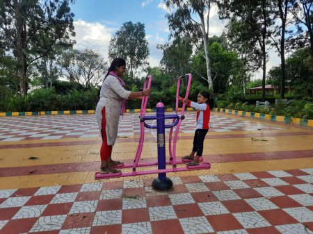 Photo for Bangalore, Karnataka, India-June 10, 2023: Closeup of beautiful people working on public gym equipment in the park at Machohalli Forest Gate - Royalty Free Image