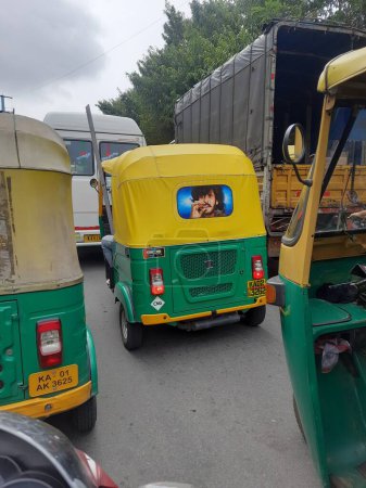 Téléchargez les photos : Bangalore, Karnataka, Inde-Sep 14, 2023 : Gros plan de rickshaw automobile de passager de couleur verte et jaune et arrière de l'acteur de légende de Kannada et directeur Real Star Upendra dessin. - en image libre de droit