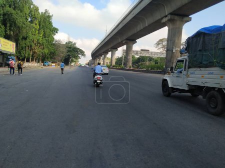 Téléchargez les photos : Bangalore, Karnataka / Inde-20 avril 2020 : Gros plan de la magnifique route d'asphalte de Bangalore avec le pont du métro Namma ou le survol d'un côté près du Goraguntepalya. En raison de Covid 19 Lock down Road est vide. - en image libre de droit