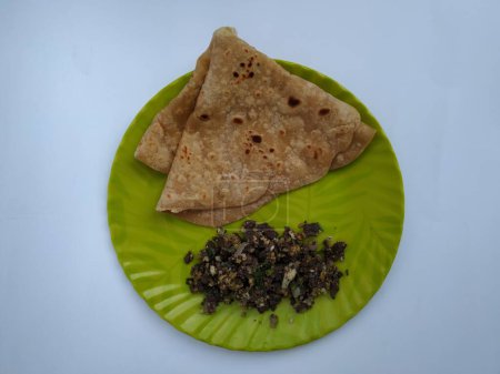 Nahaufnahme von Ziegenblut-Braten mit Eiern Kombination mit Chapathi oder Parota in einem grünen Teller isoliert auf weißem Hintergrund.
